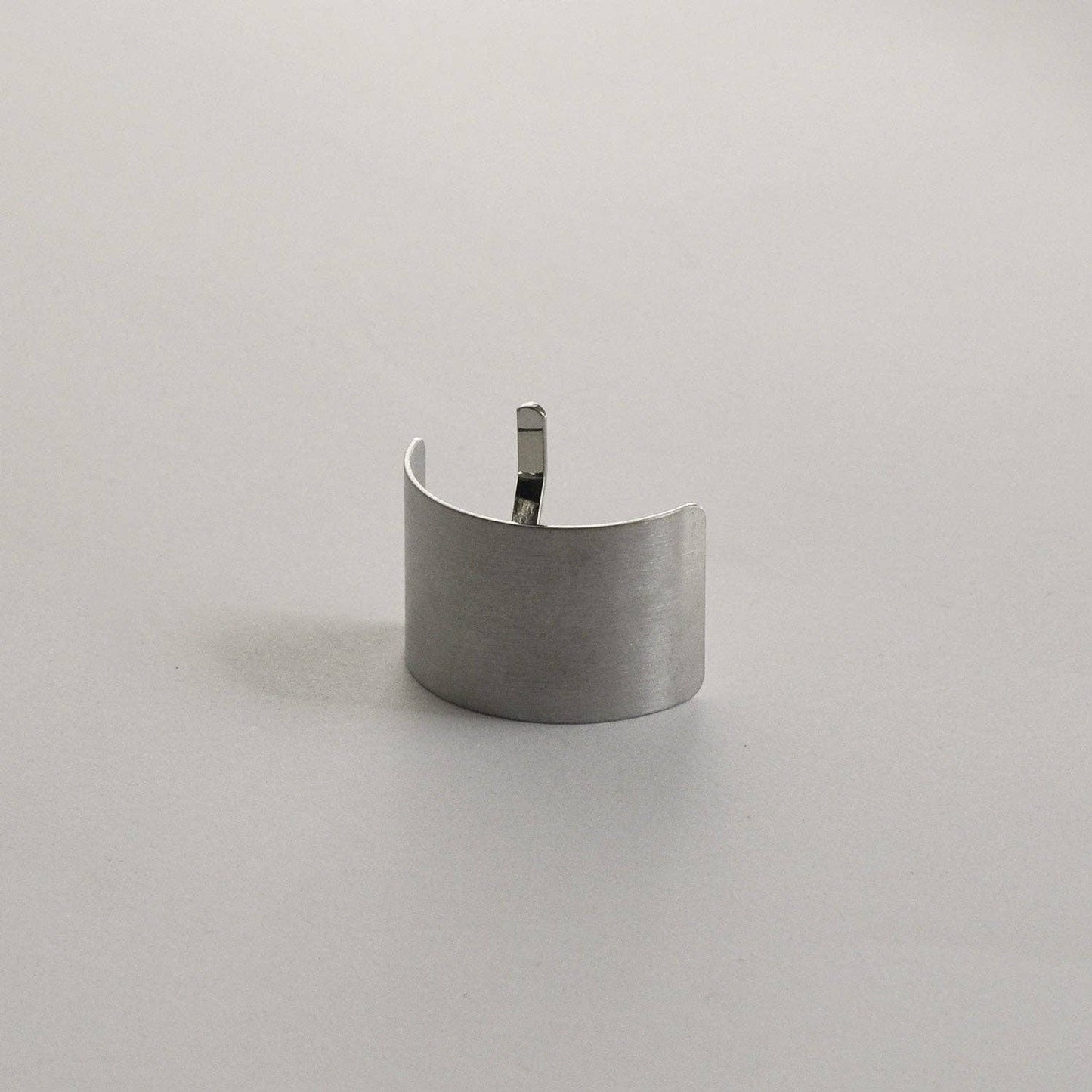 Upright view of the silver rectangular metal ponytail cuff stick highlighting its brushed metal finish.