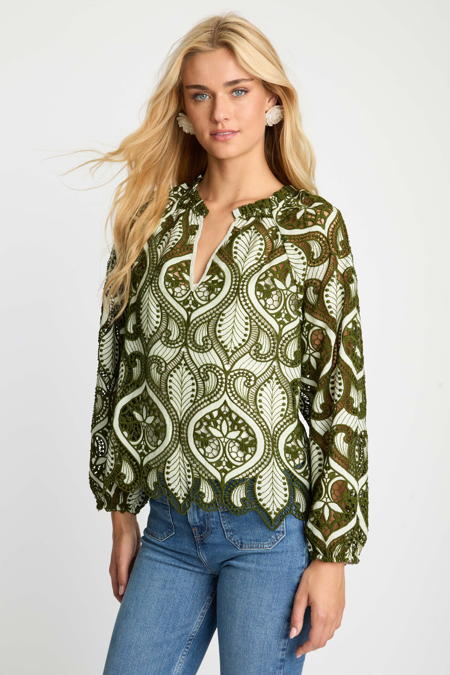 Angled front view of the Miki Top showcasing intricate green embroidered cut-out detailing, relaxed silhouette, long sleeves, and scalloped hem.
