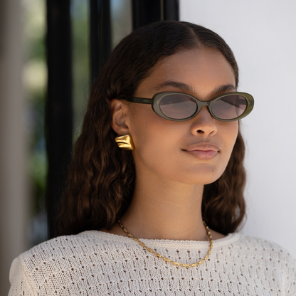 Model wearing the Mimi acetate oval sunglasses in olive with brown tinted lenses.