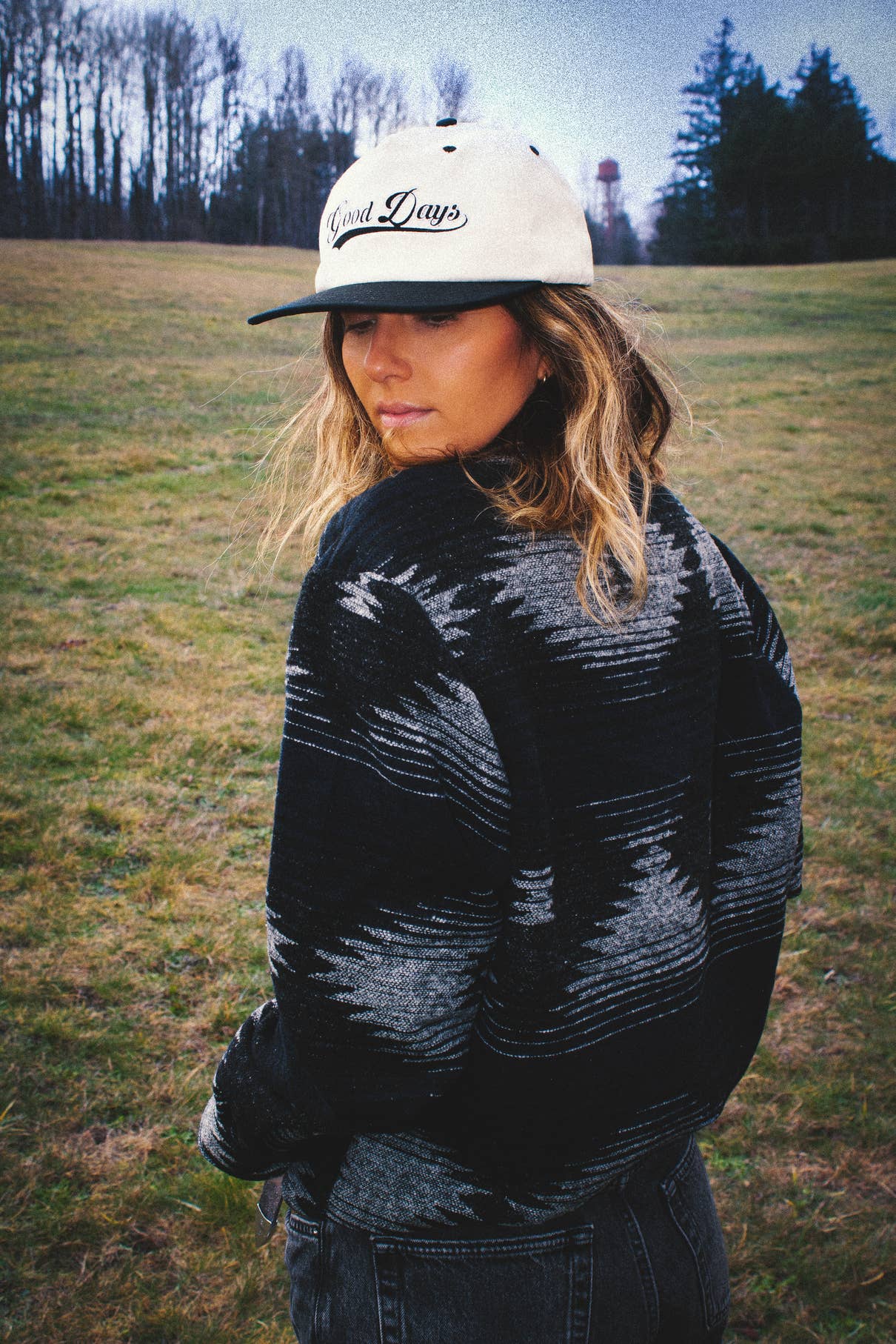 Lifestyle back view of the Moab Mid-Weight Button Down in black and blue worn outdoors on a grassy field.