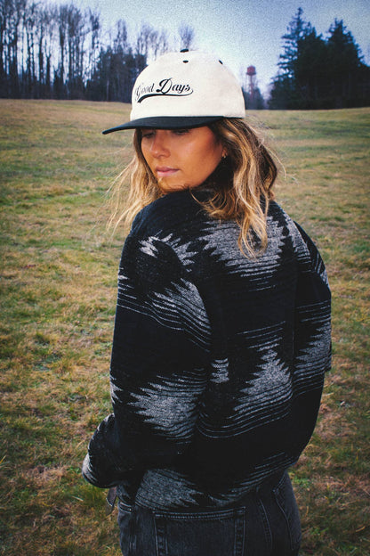 Lifestyle back view of the Moab Mid-Weight Button Down in black and blue worn outdoors on a grassy field.