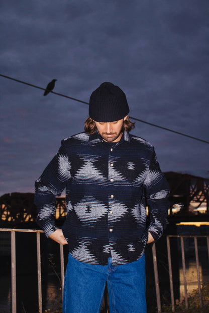 Model wearing the black and blue Moab Mid-Weight Button Down during an evening outdoor shoot with relaxed fit styling.