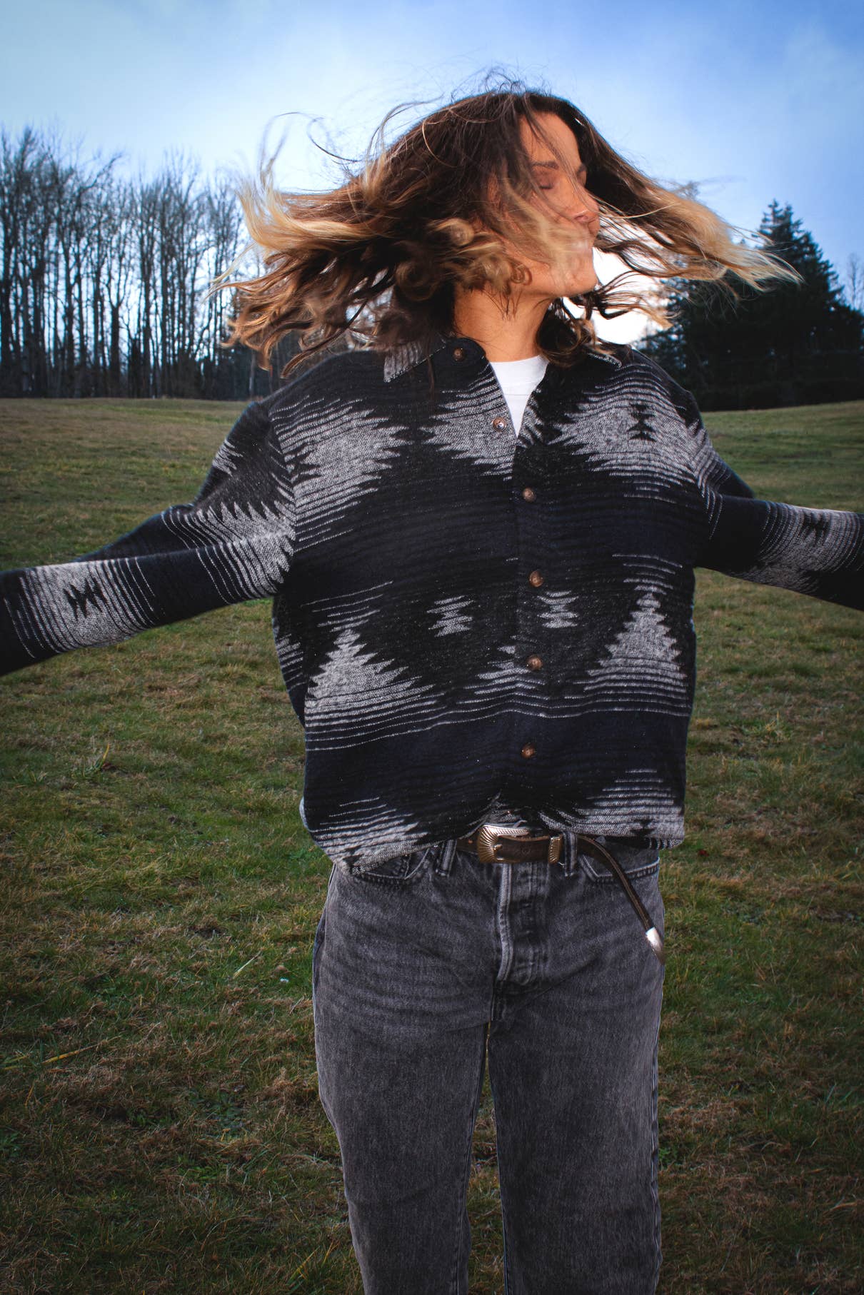 Model wearing the black and blue Moab Mid-Weight Button Down with Aztec pattern while moving outdoors in a grassy field.