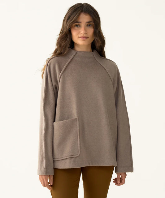 Model wearing the Hikerkind Mock Neck Pile Fleece from the front, styled with brown pants and showing its relaxed oversized fit and patch pocket.