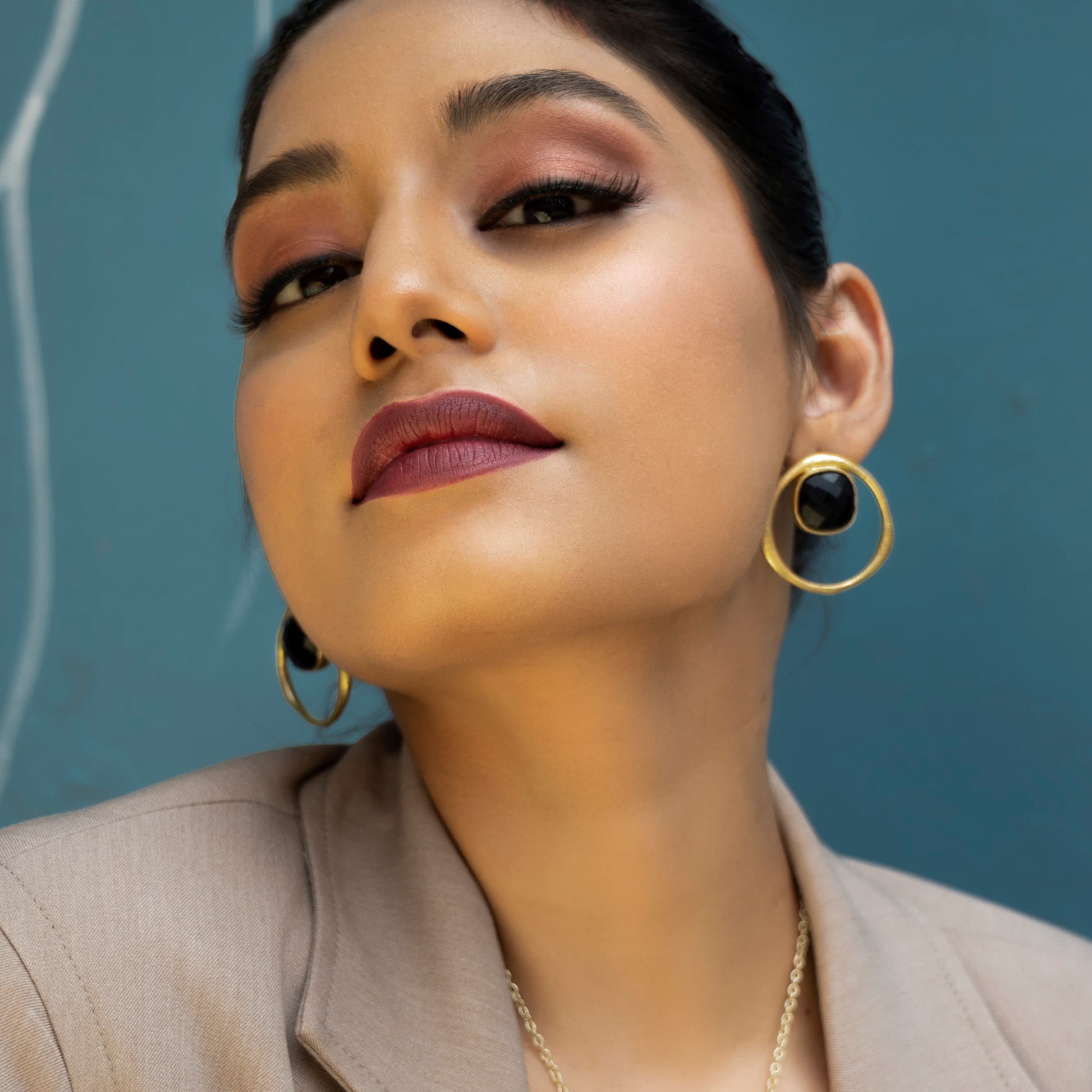 Close-up of a model wearing black onyx stud earrings with gold-plated circular frames.