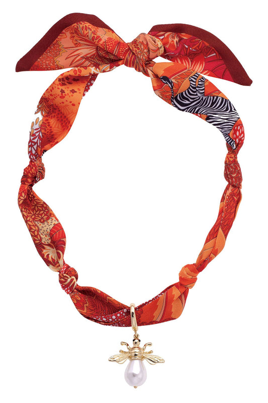 Monroe Pearl Bumble Bee Scarf Necklace in Orange/Red featuring a patterned orange and red scarf necklace with a gold bumble bee charm and pearl drop accent.