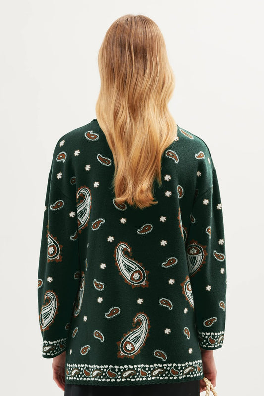 Back view of the Morla Cardigan in green showcasing a full paisley pattern with small white dot accents and contrasting border trim along the hem and cuffs.