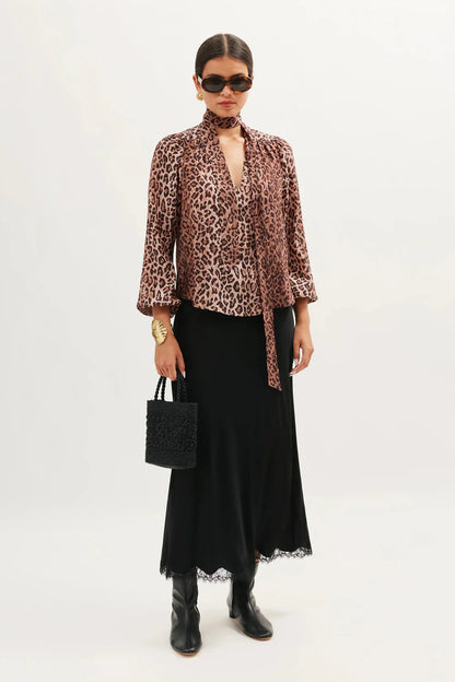 Model styling the Moss leopard print silk blouse with a black satin skirt and knee-high boots