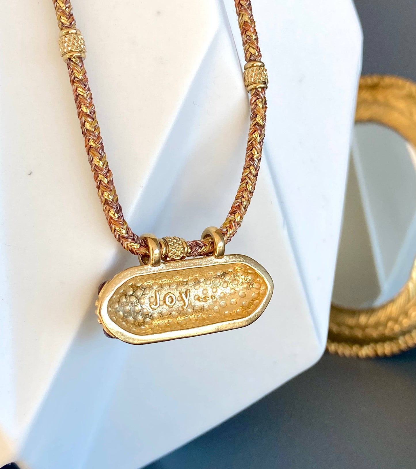 Reverse view of the Mumbai Necklace pendant showing the engraved word Joy.