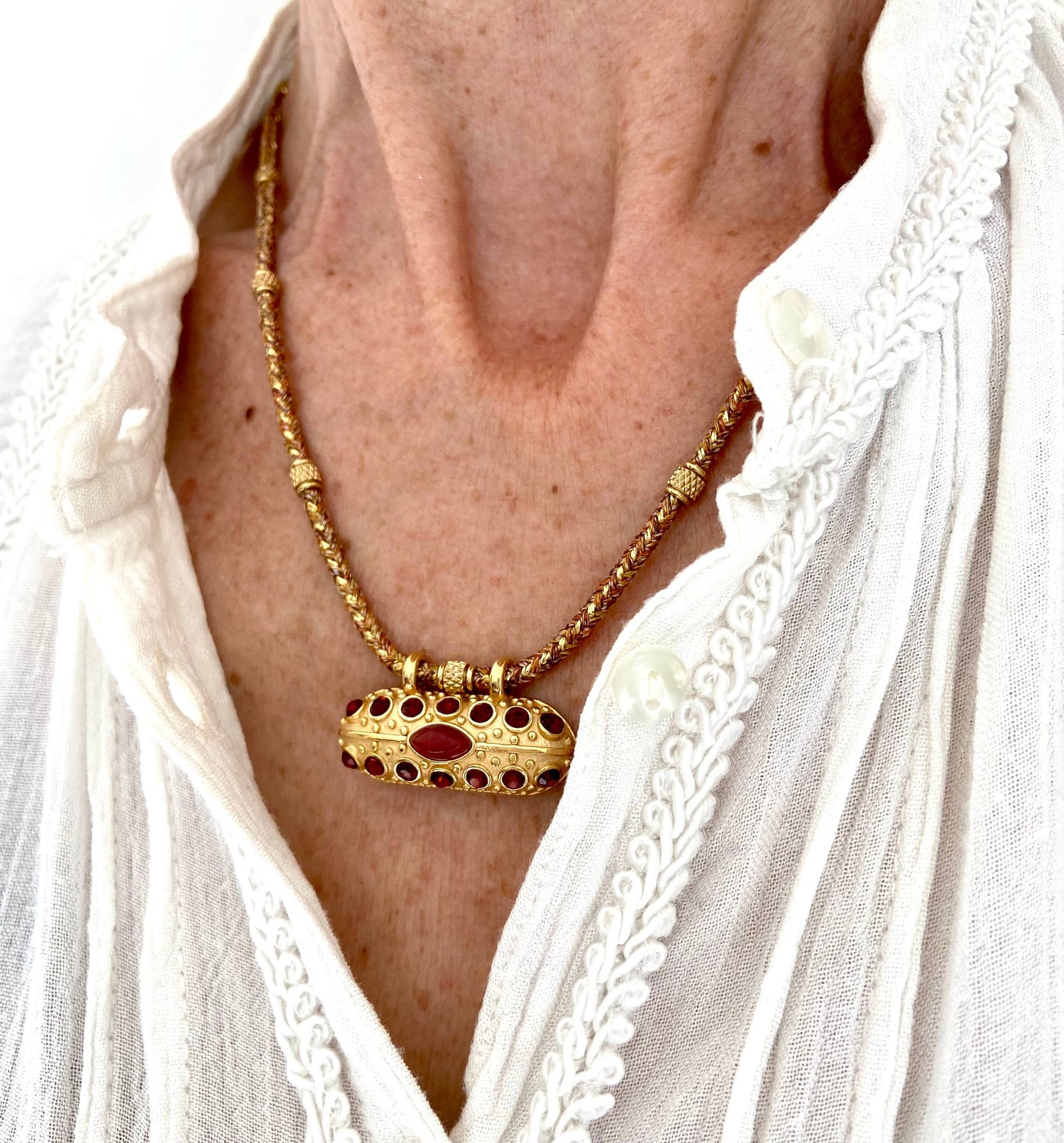 Close-up of a woman wearing the Mumbai Necklace with a gold-plated carnelian and crystal talisman pendant.