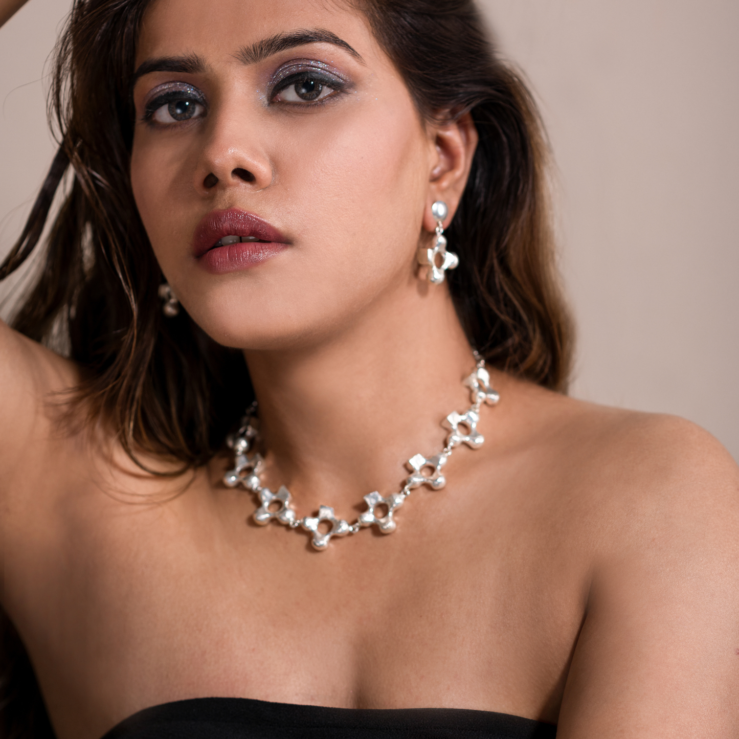 Model in a black strapless top wearing the silver-plated cross necklace and coordinating earrings.