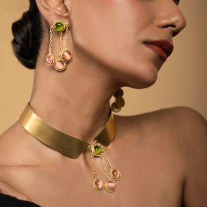 Model in side profile wearing pink and green gemstone dangle earrings with the coordinating gold collar necklace.