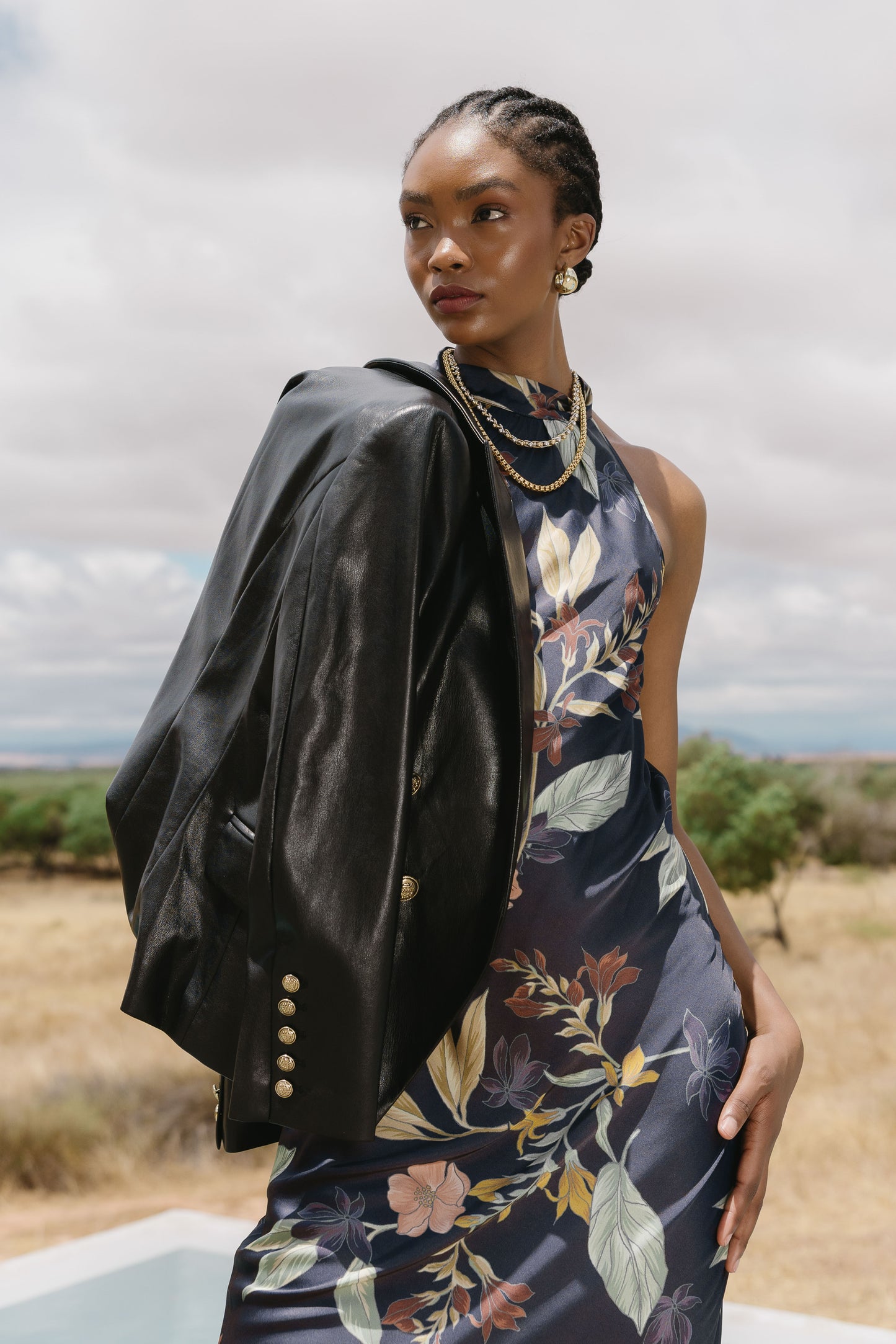 Model wearing the Naf Dress in Sundown Floral styled with a black jacket in an outdoor editorial setting