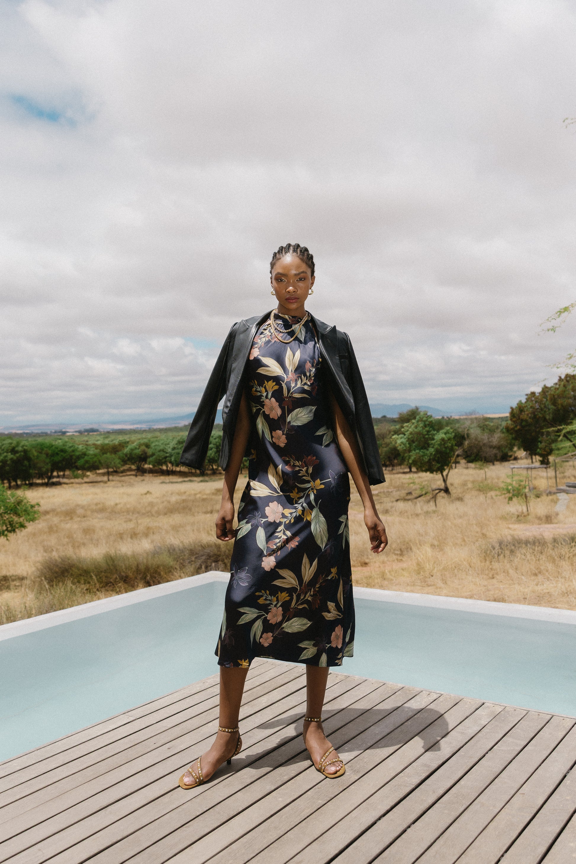 Full-length outdoor view of model wearing the Naf Dress in Sundown Floral, showing the sleek silhouette and floral print