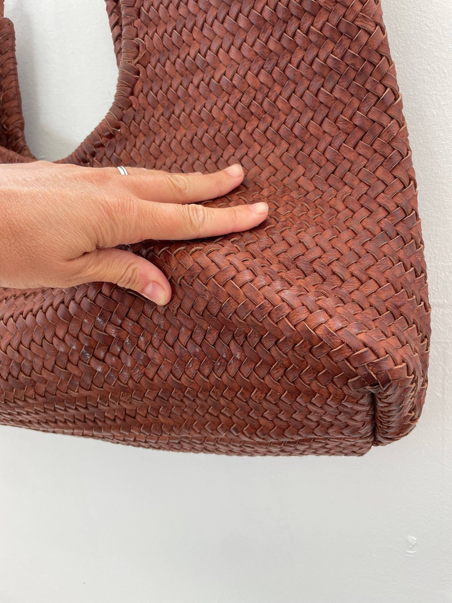 Close-up of the Narmada Brown Bag base highlighting the woven leather texture, structured corners, and handcrafted construction.