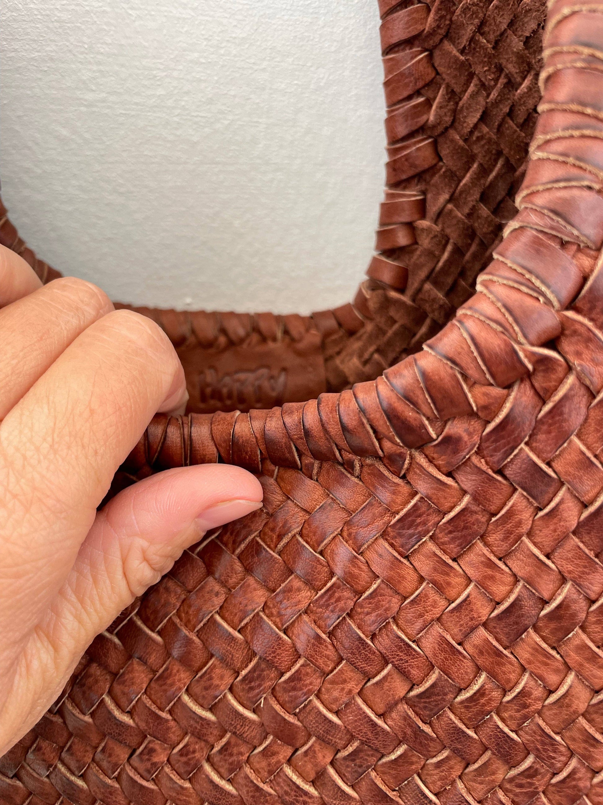 Close-up of the Narmada Brown Bag featuring braided leather shoulder straps and hand-finished woven leather trim.