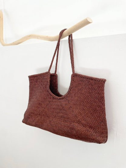 Narmada Brown Bag in handwoven brown leather displayed hanging, featuring an open-top design and double shoulder straps.