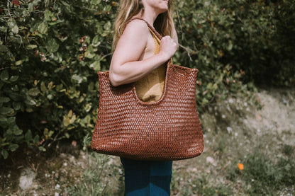 Side view of the Narmada Brown Bag featuring a handwoven leather exterior, open-top design, and comfortable shoulder straps.