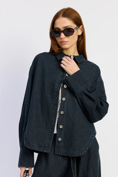 Model wearing the Natalia Top in washed vintage indigo denim with a classic collar, oversized fit, button-down front, and curved hemline.
