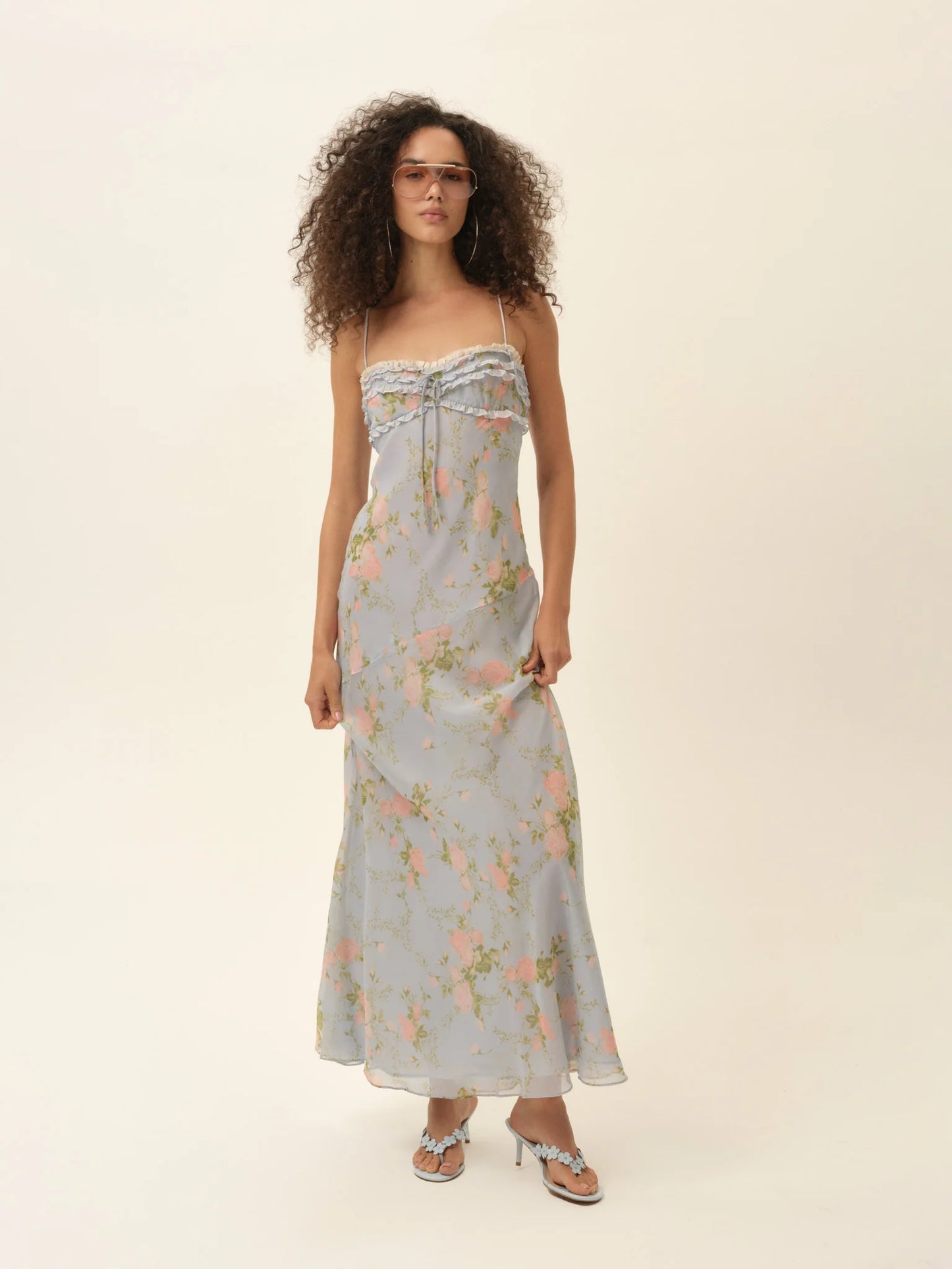 Model wearing the Natalie Maxi Dress in dusty blue floral print with delicate ruffles and a soft flowing maxi silhouette.