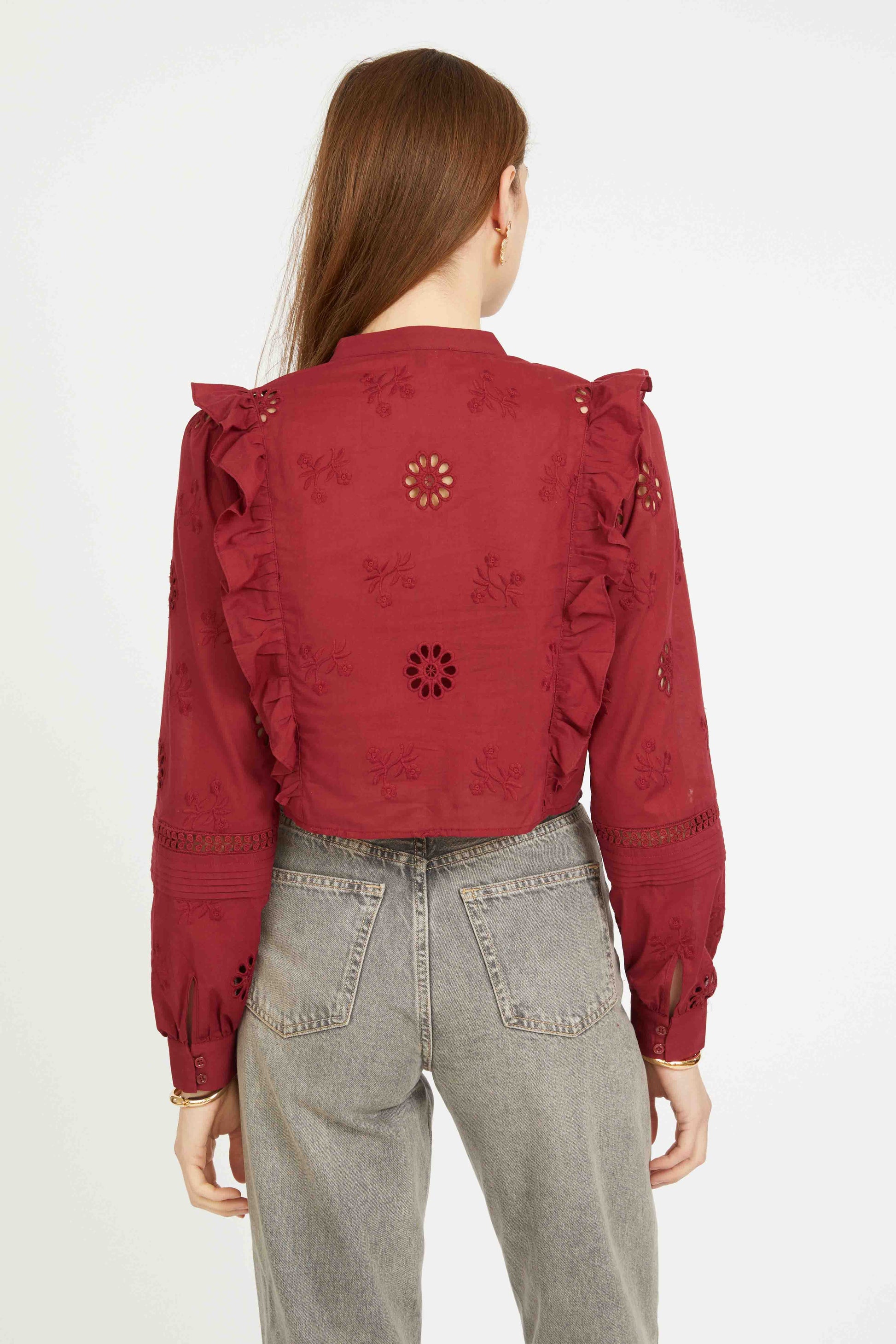 Back view of the Nelly Top in cabernet showing embroidered floral details, ruffle accents, and cropped long sleeve silhouette.