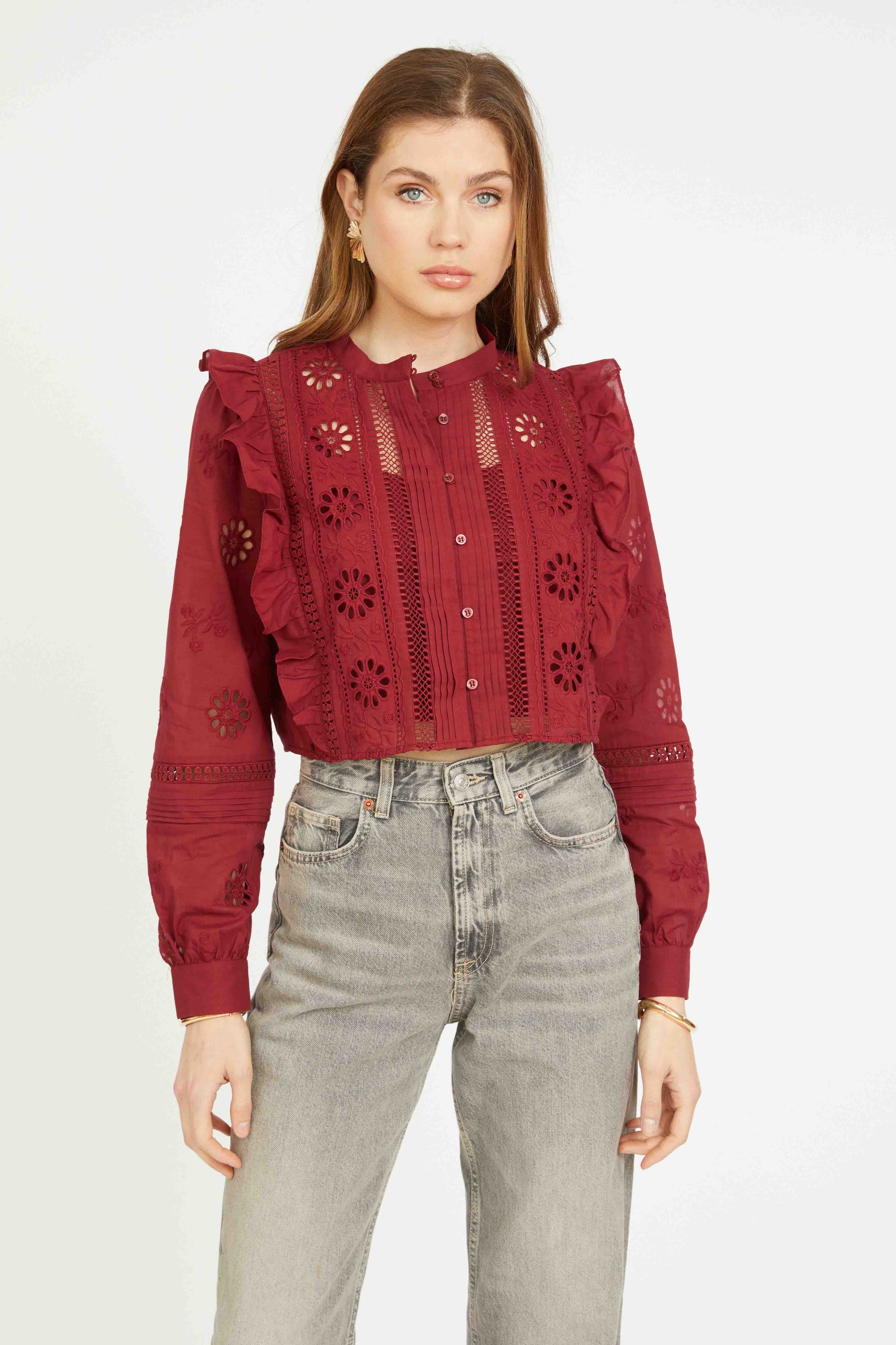 Close-up front view of the Nelly Top in cabernet with intricate eyelet cut-outs, ruffle detailing, pintuck accents, and long sleeves.