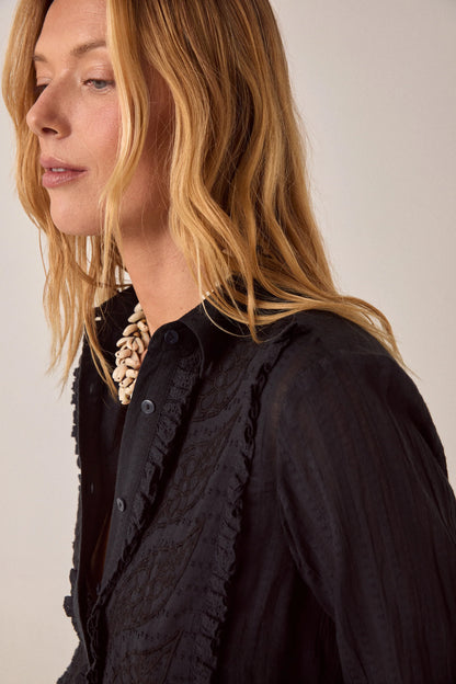 Side close-up of the Night Fever Javiera Blouse in Onyx showcasing tonal floral embroidery, soft ruffle trim, and lightweight textured cotton.