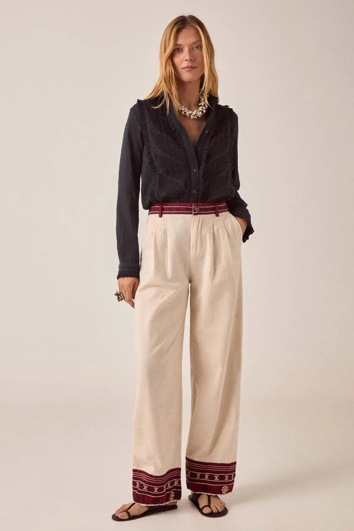 Full-length view of the Night Fever Javiera Blouse in Onyx paired with embroidered cream wide-leg trousers and sandals for a relaxed bohemian look.