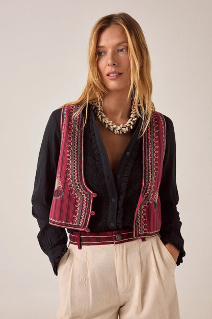 Model wearing the Night Fever Javiera Blouse in Onyx layered with an embroidered burgundy vest and styled with cream embroidered trousers.