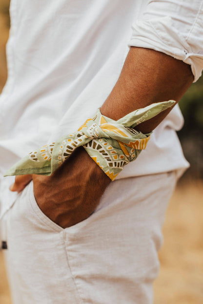 No. 044 Hazel Bandana folded and tied around a woman’s wrist with an all-white outfit.