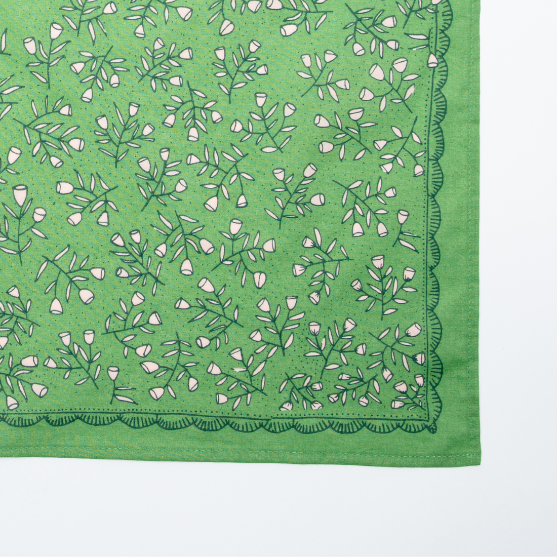 Close-up of the Kelly green Posey Bandana showing its cream floral pattern and ornamental border.