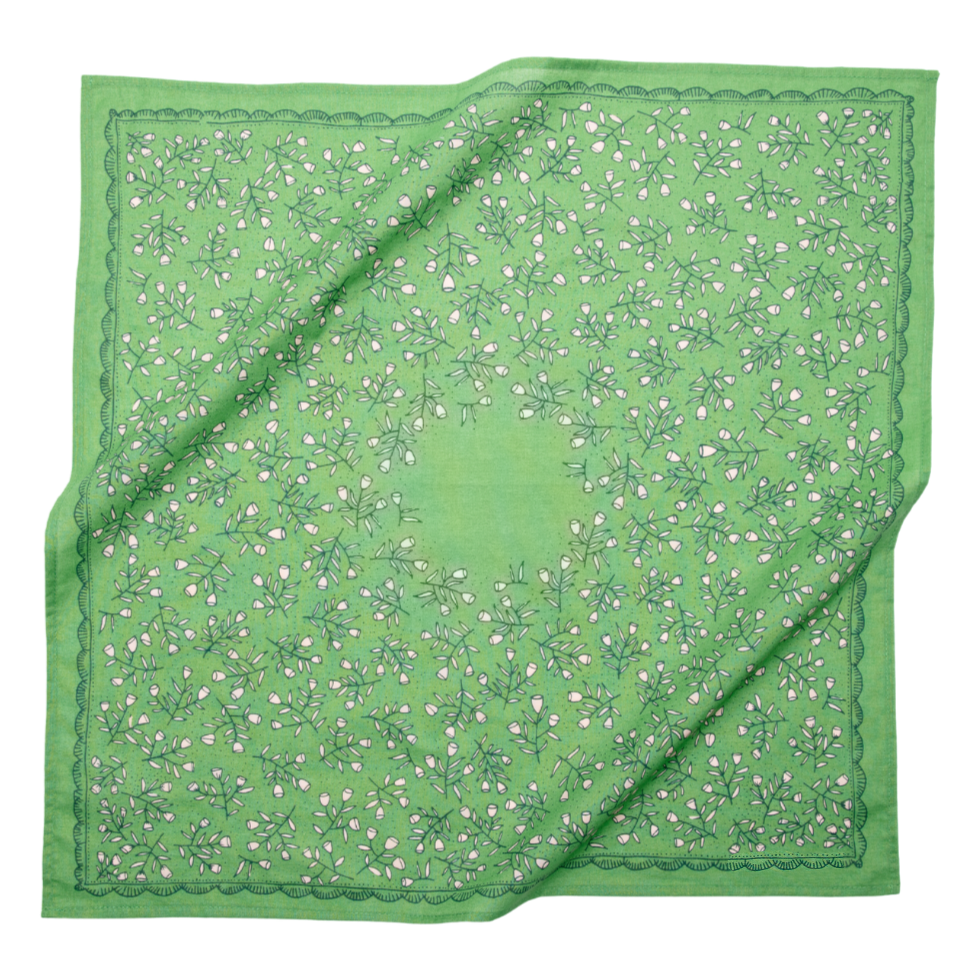 Kelly green cotton bandana with a cream calico floral pattern and decorative border shown loosely draped.