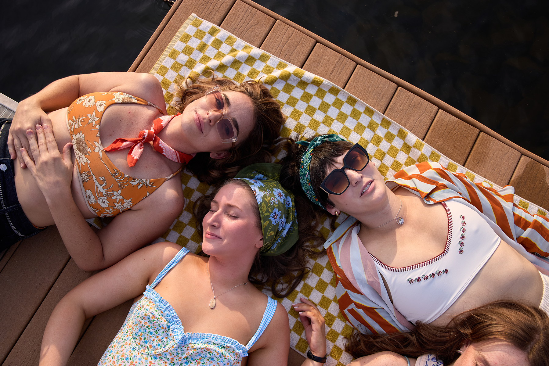 Clara bandana styled on a group by the lake, featuring olive green floral prints worn as hair and neck accessories.