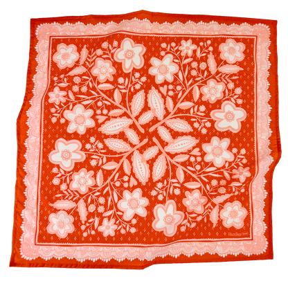 Red-orange and pink Lacey Bandana laid flat, featuring an intricate floral pattern and decorative border.