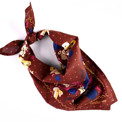 Close-up of the No. 150 Meg Bandana showing indigo, burgundy, purple, and cream flowers on chocolate brown cotton.