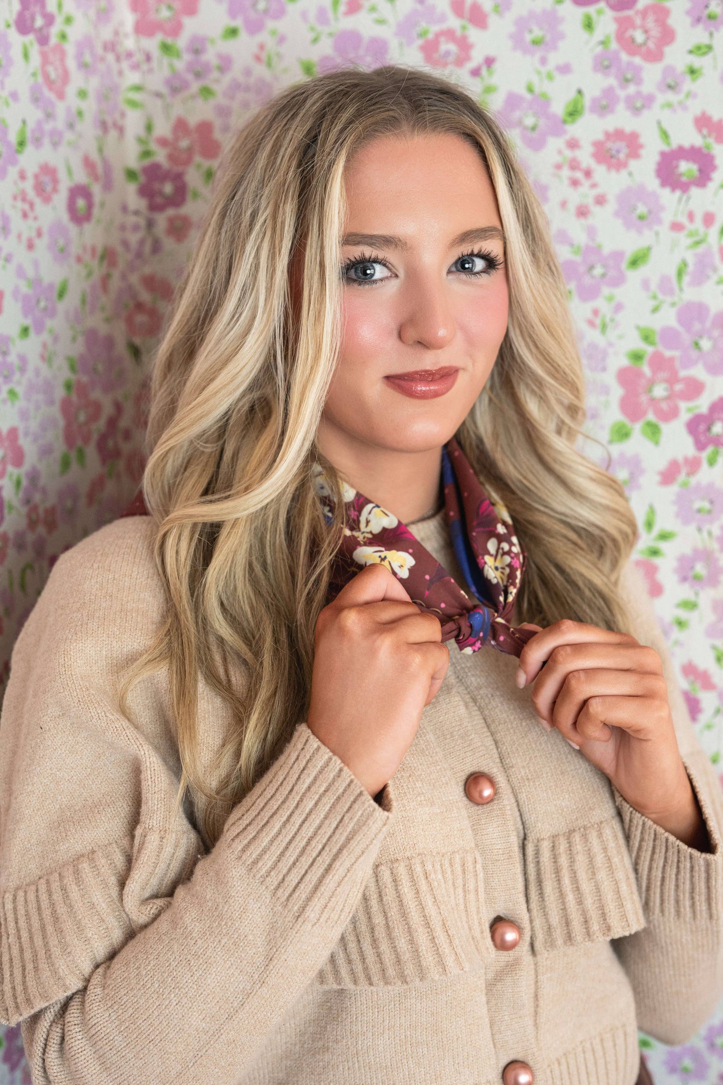 Woman holding the No. 150 Meg Bandana open to show its full chocolate brown floral design.
