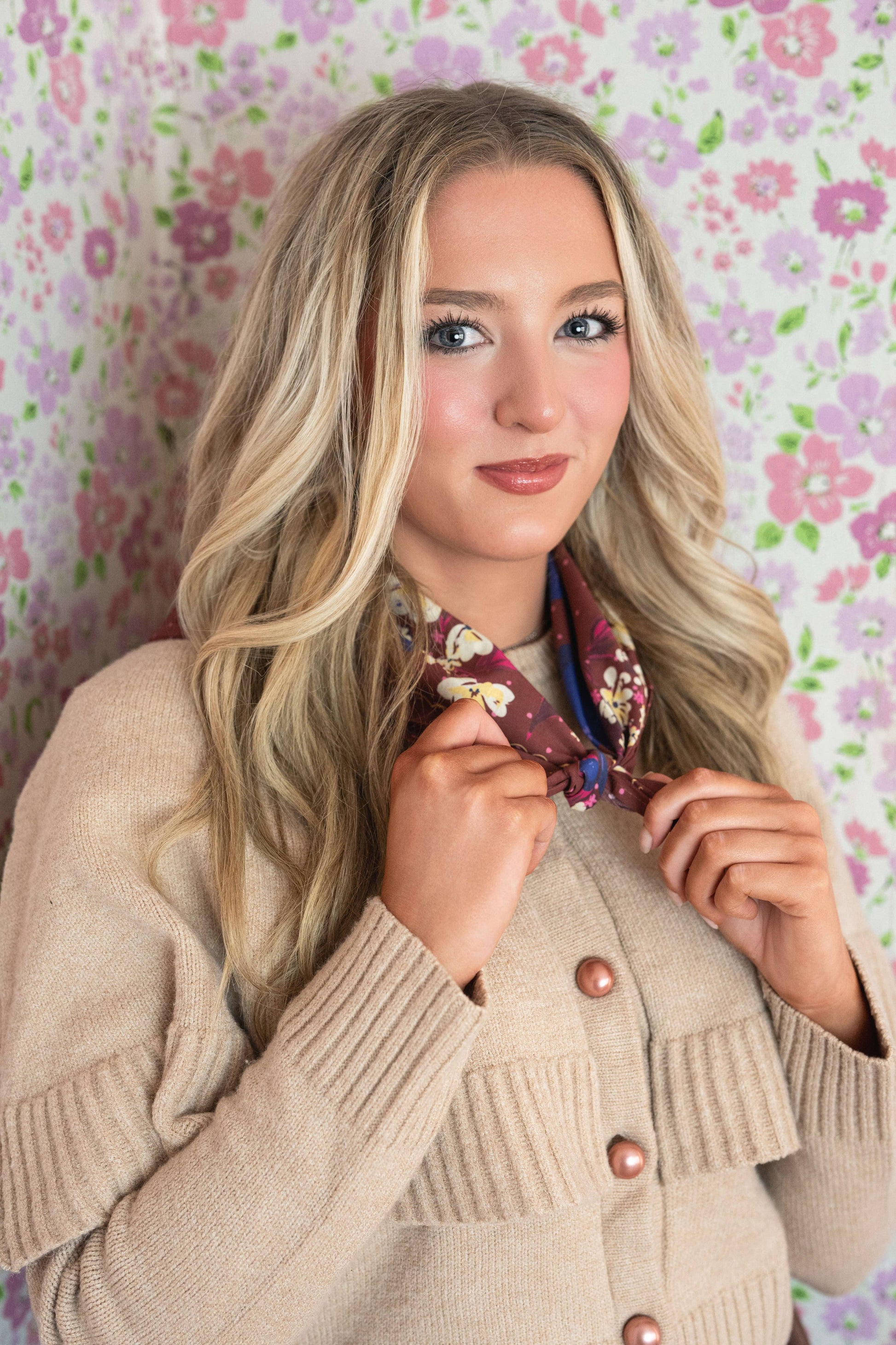 Woman holding the No. 150 Meg Bandana open to show its full chocolate brown floral design.
