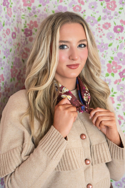 Woman holding the No. 150 Meg Bandana open to show its full chocolate brown floral design.