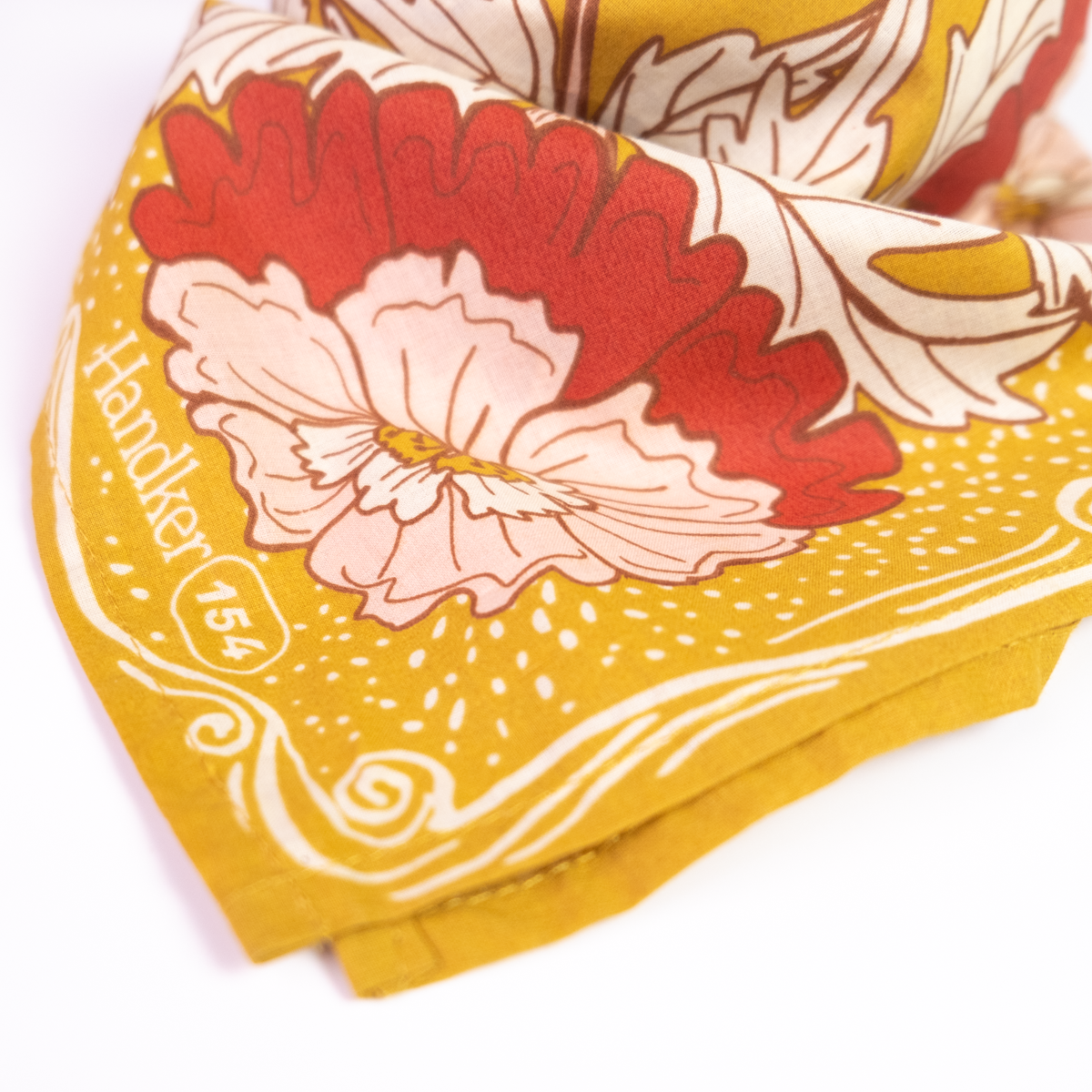 Close-up of the Ruthie Bandana corner showing the pink floral design and decorative ochre gold border.