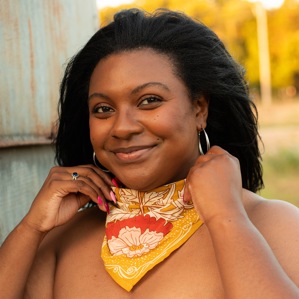 Model wearing the Ruthie Bandana as a neck scarf, highlighting its warm ochre gold and pink floral design.