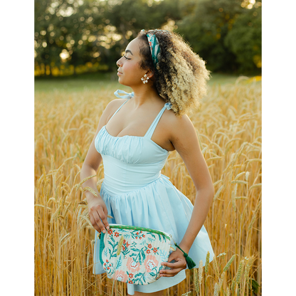Woman styling the No. 156 Willa Bandana at her waist with a light blue dress in a field.