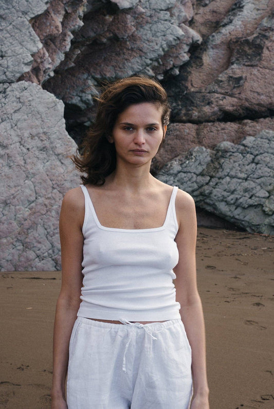 Front view of the Organic Square Cami in white styled with white pants on the beach.