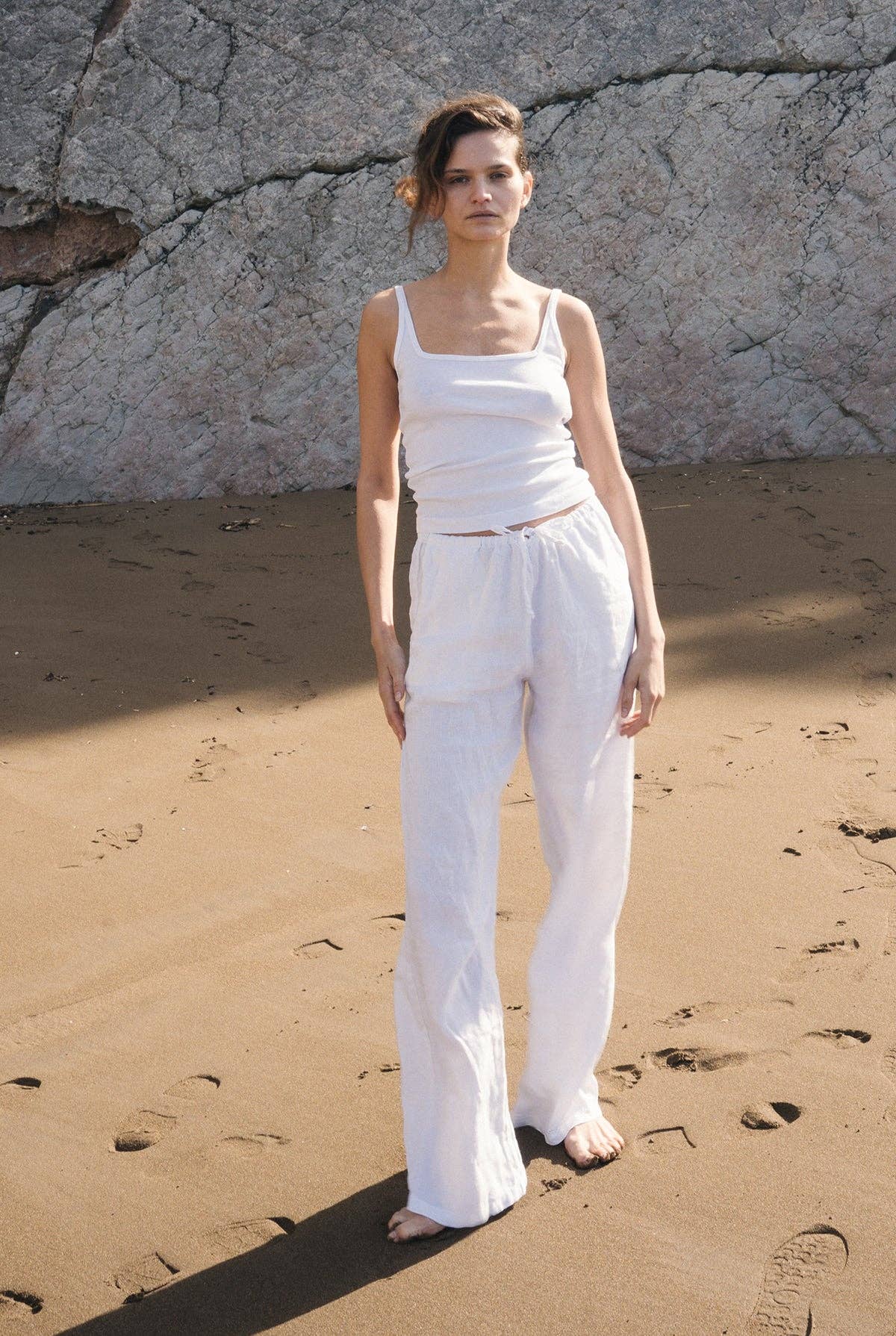Full outfit view of the Organic Square Cami in white paired with relaxed white pants on a sandy beach.