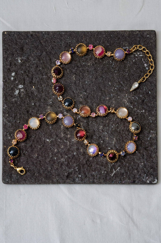 Paint Pot Layering Choker in Punk Rocks Gold displayed on a dark stone surface with multicolor round stones and gold-plated settings.