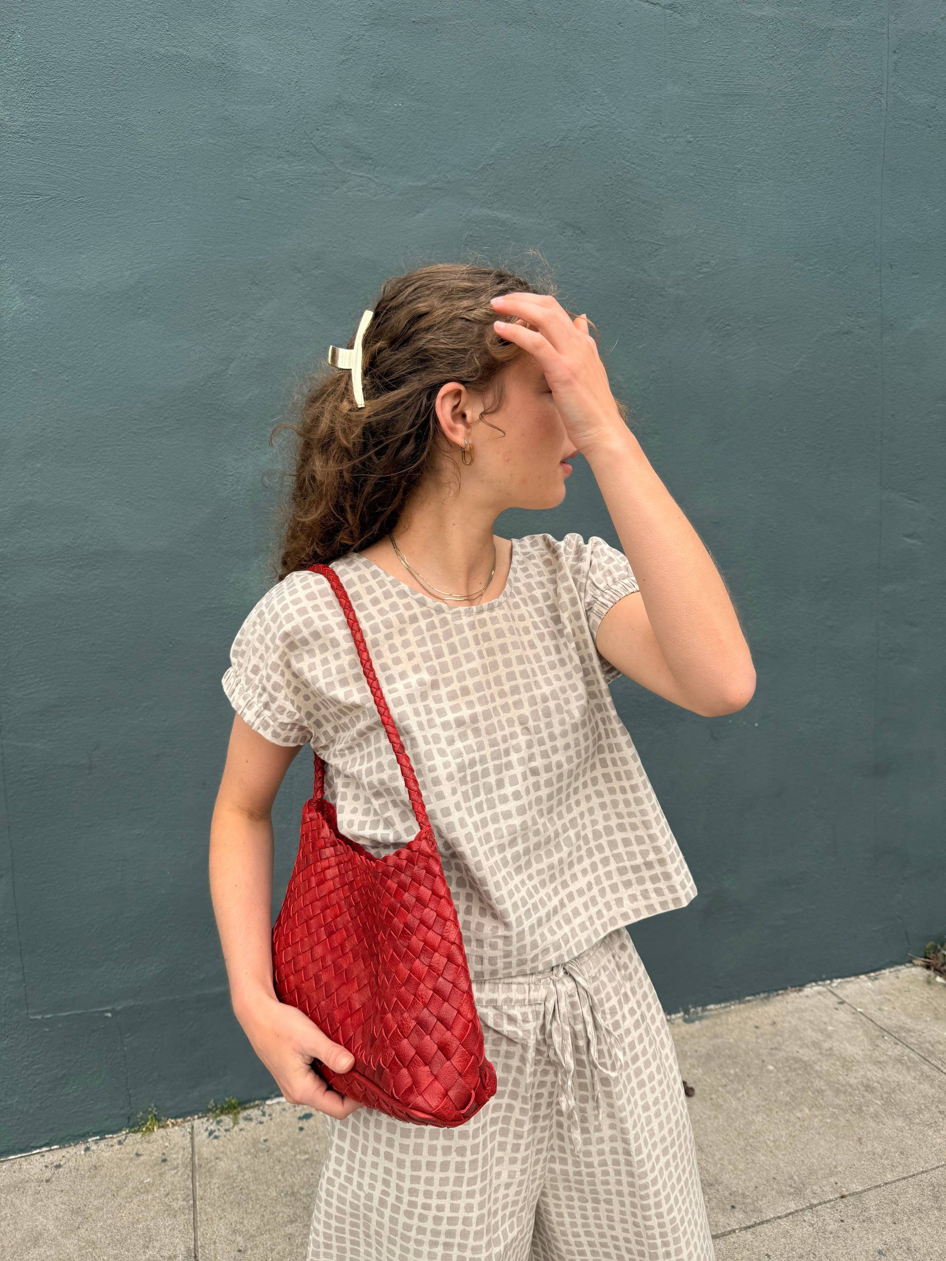Woman carrying the Palar Red Bag with a neutral printed outfit