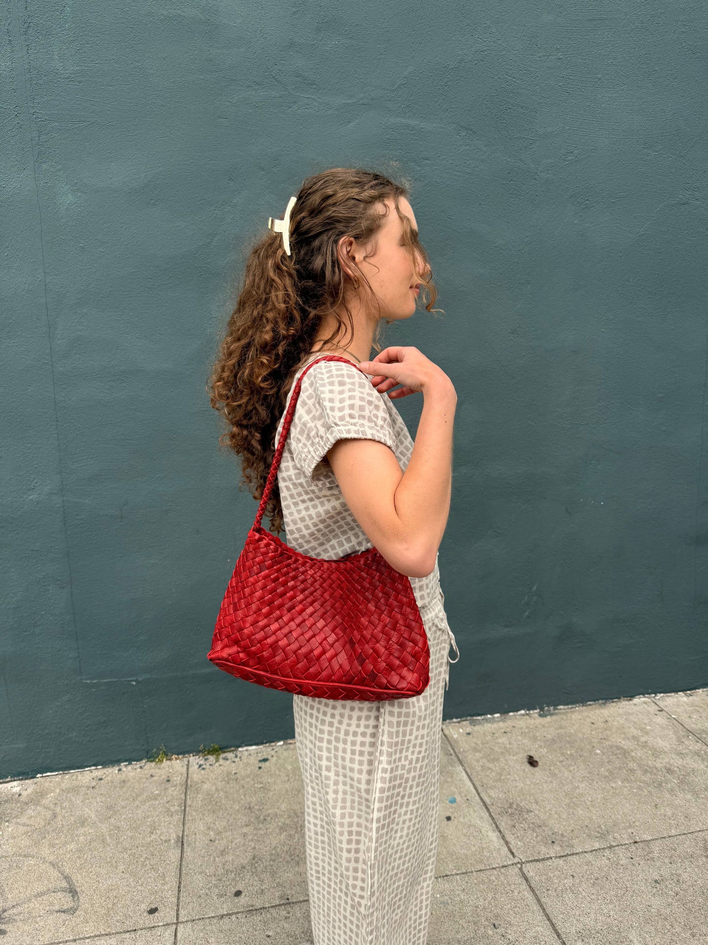Full-length view of a woman carrying the Palar Red Bag with a matching neutral set