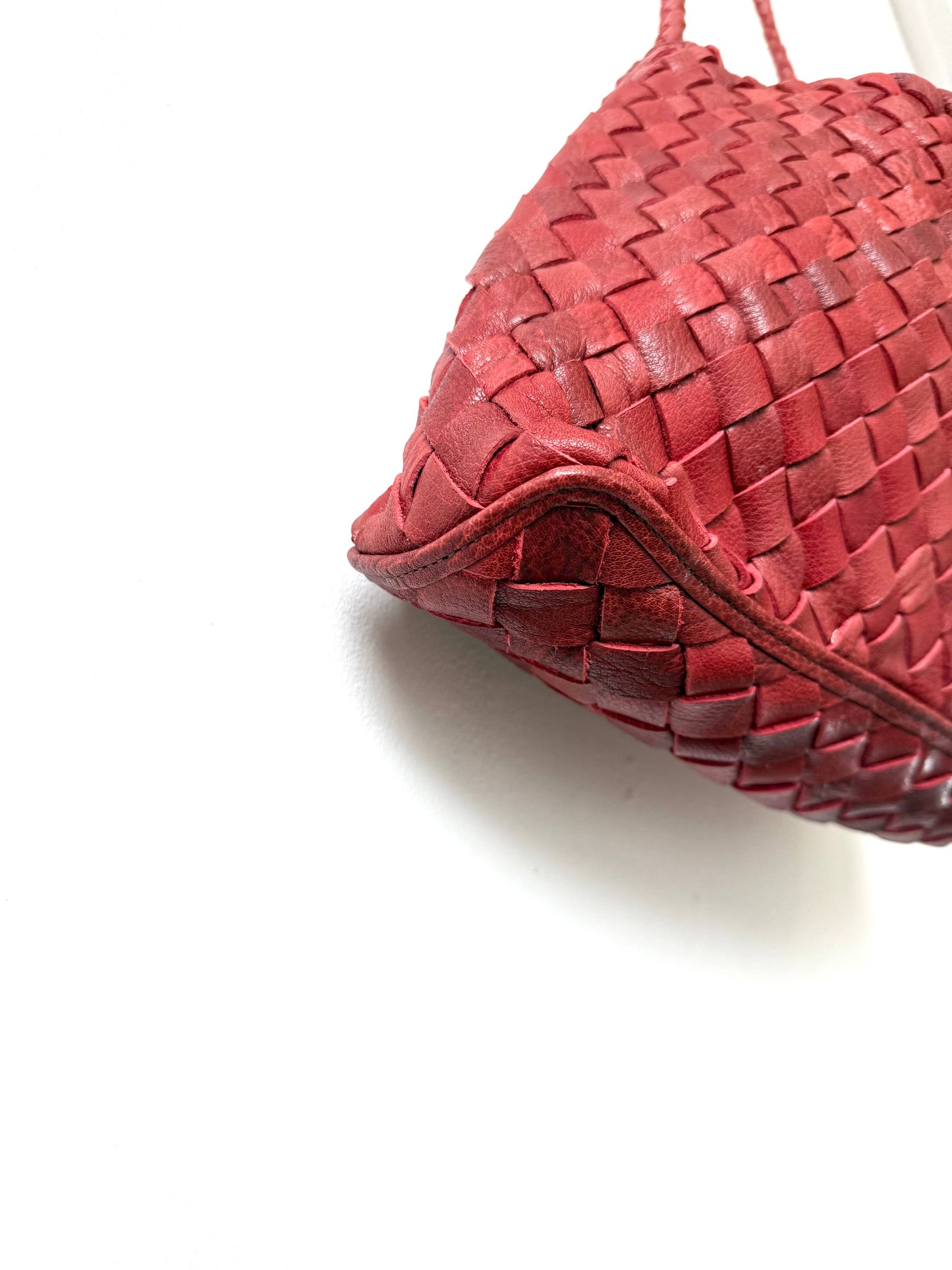 Close-up of the handwoven leather and curved base of the Palar Red Bag