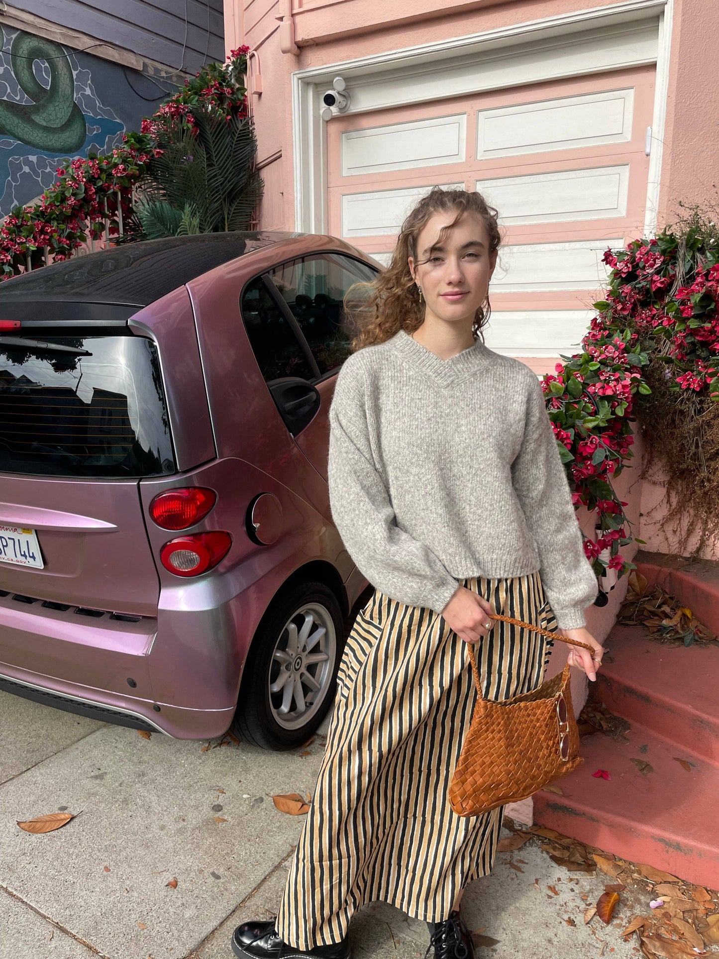 Model wearing the Palar Tan Bag crossbody with a grey sweater and striped trousers