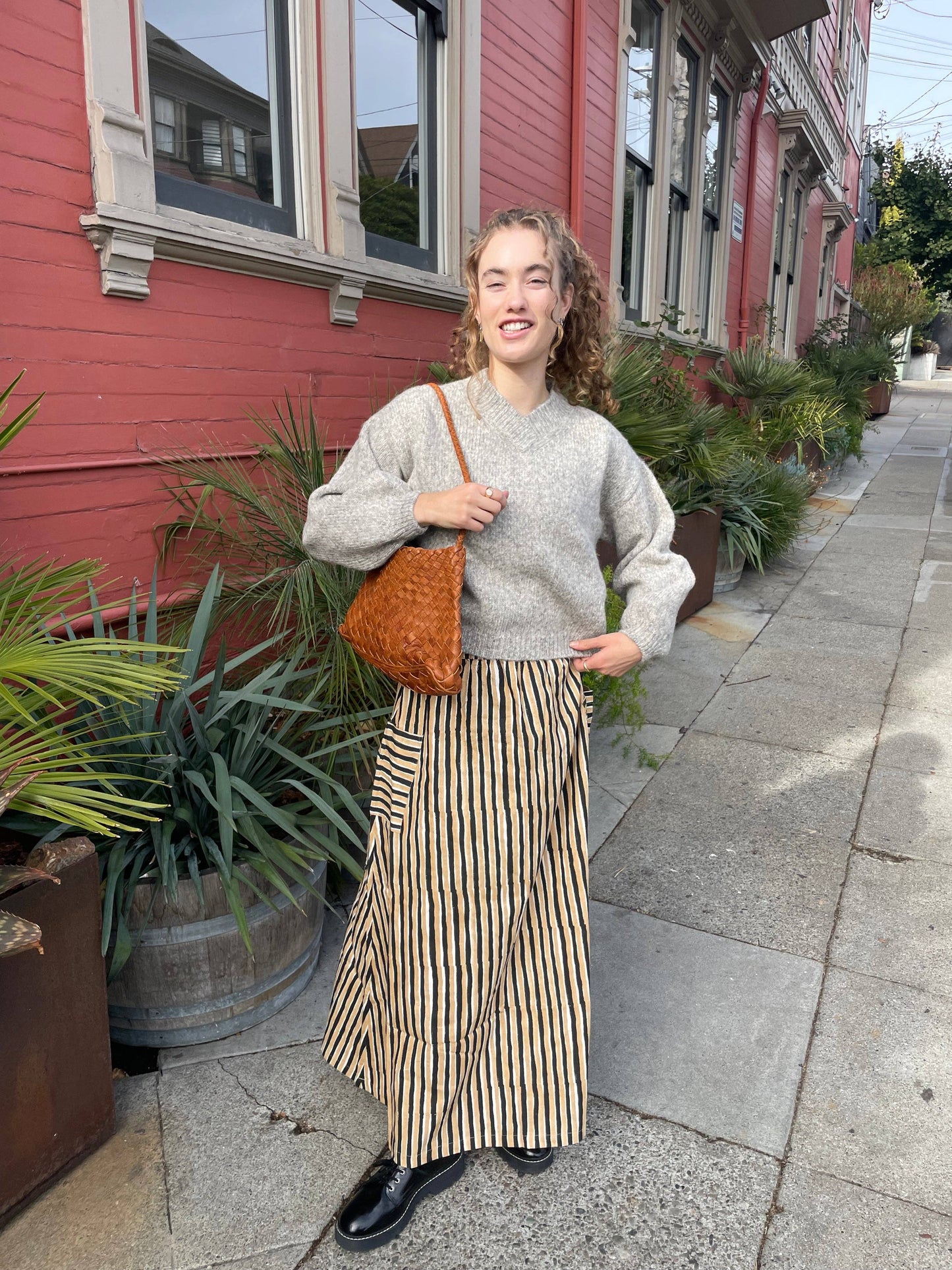 Full-length view of a model carrying the Palar Tan Bag on a city street