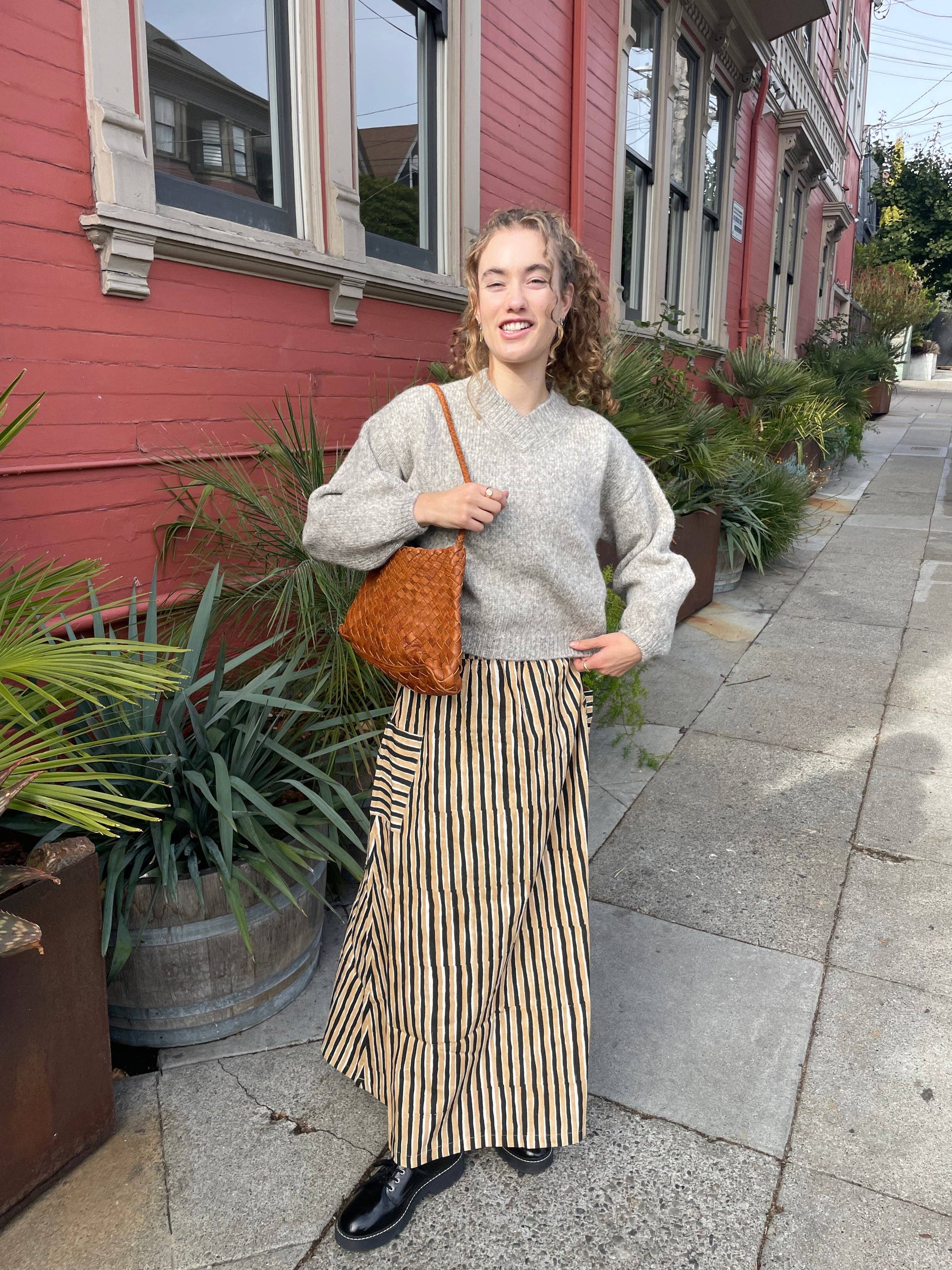 Full-length view of a model carrying the Palar Tan Bag on a city street